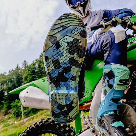 close up of muddy bottom materiis sole of messy cyan crossair x motorcycle boots