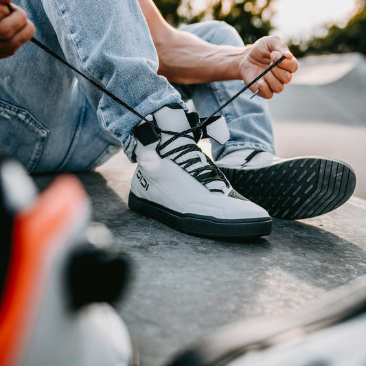 biker tying laces on a pair of white sidi riding motorcycle trainers