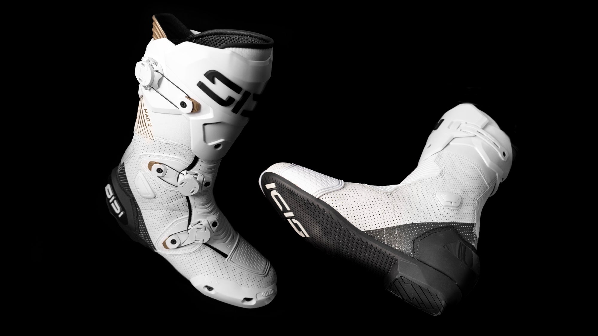 White motorcycle boots with black soles on a black background