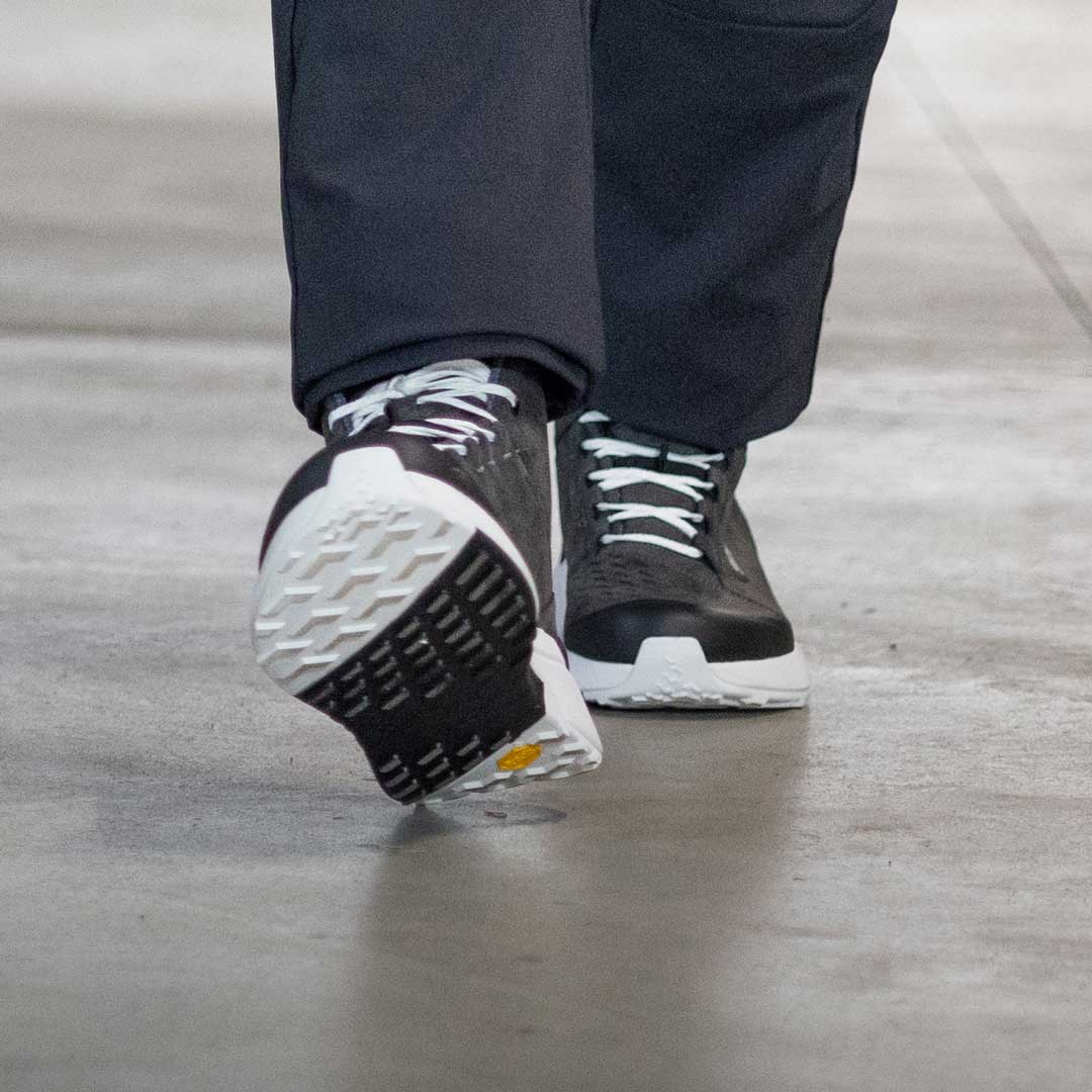 man walking wearing black and white motorbike trainers with black and white sole