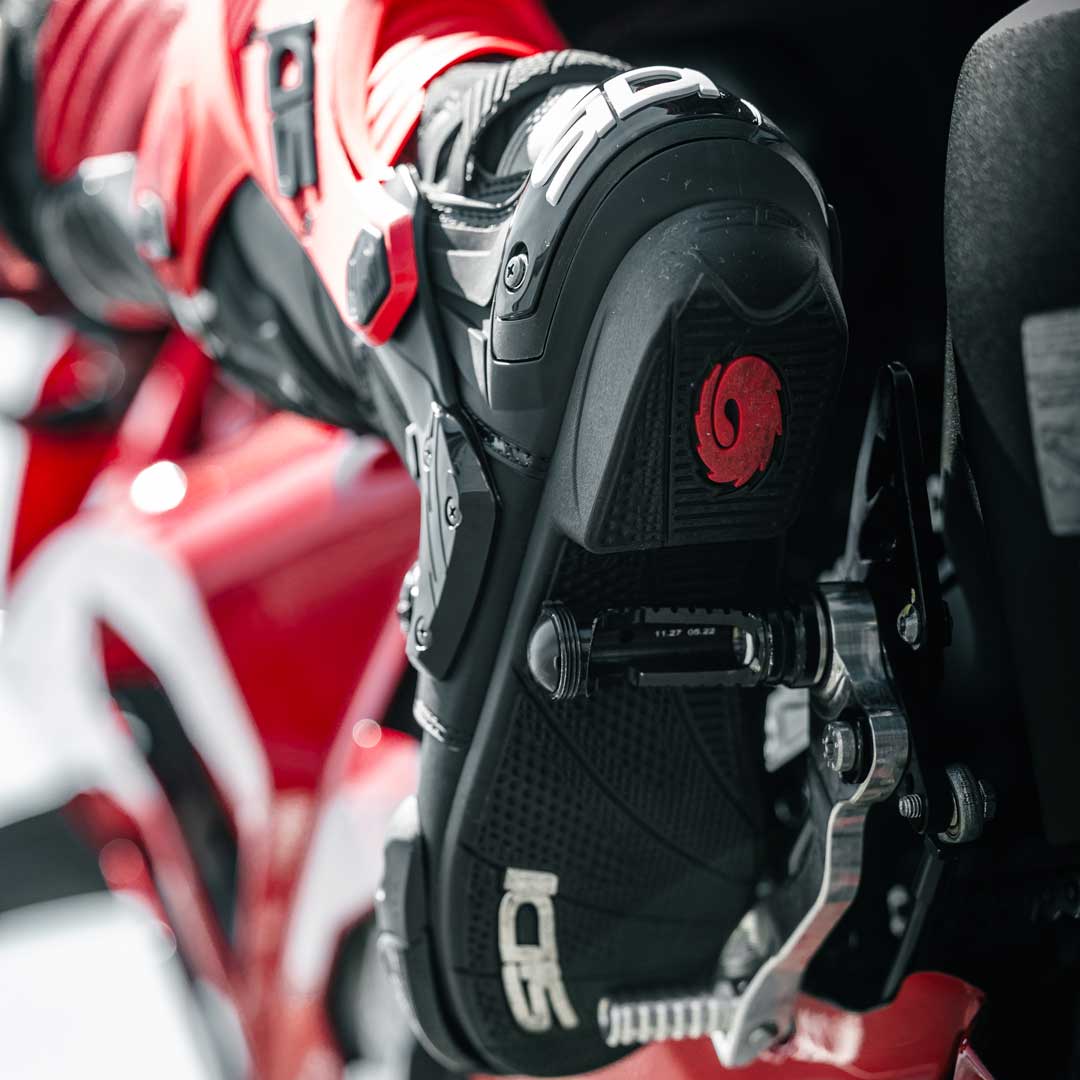 sole of black and red motorcycle shoes on motorbike