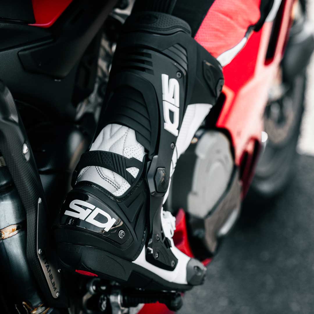 back of biker on motorbike wearing black and white motorcycle shoes