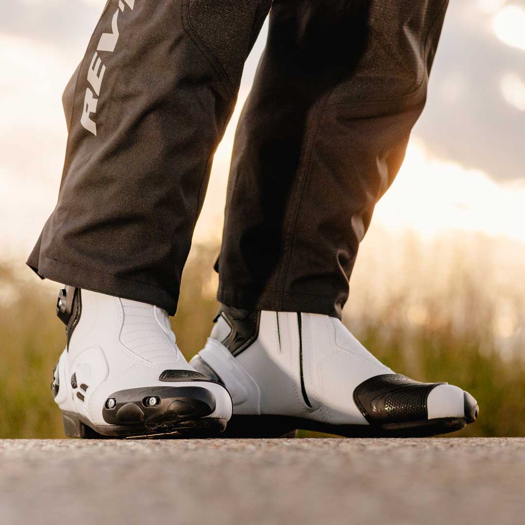 biker wearing black motorcycle trousers with black and white motorcycle boots